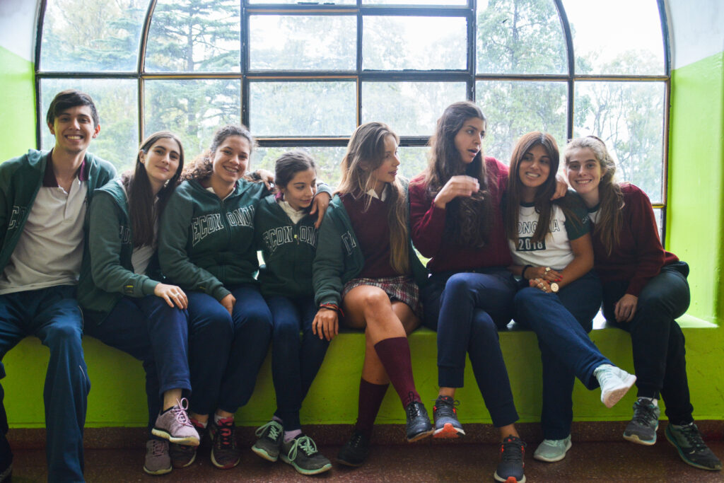 Vaihto-oppilas argentiinalaisessa koulussa koulukavereidensa kanssa penkillä koulupuvut päällä
