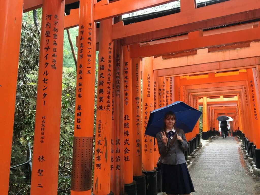 Vaihto-oppilas poseeraa sillalla sateenvarjo kädesssään Japanissa
